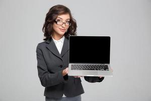 fêmea bonita confiante, mostrando a tela do computador portátil em branco