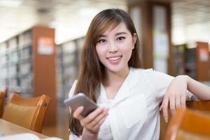 aluna linda asiática usando laptop e telefone celular foto