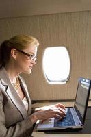 mulher de negócios usando o laptop no avião, vista lateral