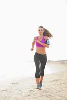 mulher jovem fitness correndo na praia foto