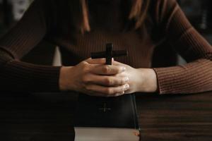 mulher sentada e estudando as escrituras. a cruz de madeira nas mãos. conceitos de educação cristã as escrituras sagradas abrem e rezam a deus. foto