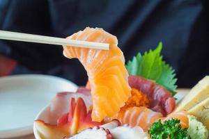 fatia de salmão em pauzinhos, comendo sashimi tigela de arroz chirashi don comida japonesa foto