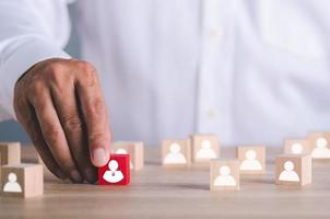 um empresário segurando um bloco de madeira vermelho sobre a mesa foto