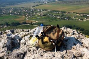 imagem de uma garrafa de plástico e uma mochila de turista em um penhasco de montanha em estado selvagem. foto