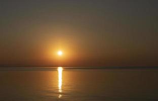 um nascer do sol bonito e colorido com um caminho ensolarado sobre o mar. foto