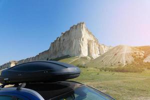 carro para viajar com um rack de teto em uma estrada de montanha, contra o pano de fundo da rocha branca. foto