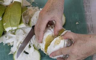 mulheres douradas descascam pomelo doce orgânico frutas tropicais segurando na mão do corpo. espeto cítrico laranja amarelo grande fresco para compartilhar. foto