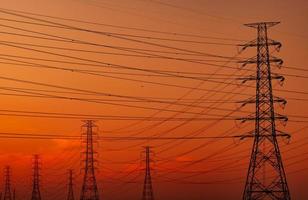 silhueta pilão elétrico de alta tensão e fio elétrico com um céu laranja. postes de eletricidade ao pôr do sol. conceito de potência e energia. torre de grade de alta tensão com cabo de arame na estação de distribuição. foto