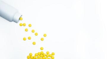 pílulas de comprimidos revestidos de filme amarelo derramando do frasco de comprimidos em fundo branco, com espaço de cópia. comprimidos de comprimidos analgésicos. nsaids pílulas para dores musculares. foto