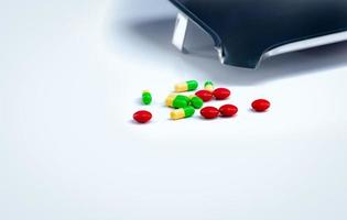 comprimidos vermelhos e comprimidos de cápsulas verde-amarelas com bandeja de drogas na mesa branca. indústria farmacêutica. vitaminas e suplementos. conceito farmacêutico. produtos de farmácia. saúde e medicamentos. foto