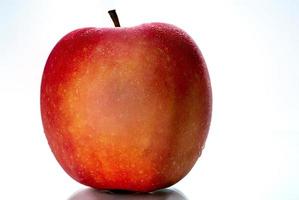 uma maçã vermelha com água cai na pele isolada no fundo branco, com espaço de cópia. fruta saudável e conceito de comida saudável. comida vegana.