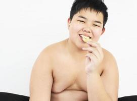 menino gordo está comendo batata frita feliz foto