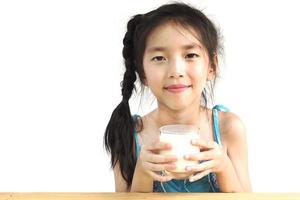 menina asiática está bebendo um copo de leite sobre fundo branco foto