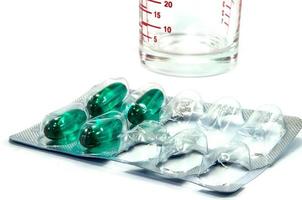 comprimidos de remédio com vidro no fundo branco foto