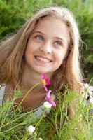 retrato de adolescente loira sorridente acima de flores, hortaliças