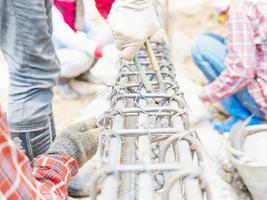 trabalhadores da construção civil estão instalando hastes de aço em viga de concreto armado foto