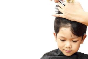 um menino é cortado o cabelo pelo cabeleireiro isolado sobre fundo branco foto