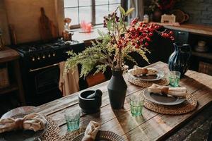 servido mesa de jantar bem decorada com vasos de guardanapos de pratos. interior do fundo da cozinha. conceito de restauração. Estilo retrô. design de interiores foto