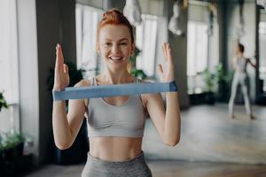 retrato de jovem ruiva desportiva em roupas esportivas com elástico de resistência foto