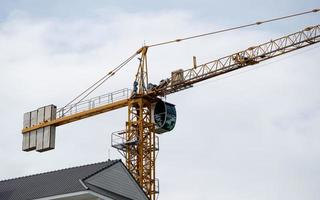 o guindaste de torre alta está trabalhando sobre o prédio no canteiro de obras. foto