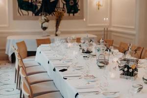 mesa de jantar lindamente decorada para celebração no café ou restaurante. cores brancas. evento festivo. banquete. mesa de casamento com copos e pratos foto