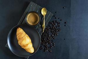 café da manhã café e croissant no prato na mesa de madeira. foto