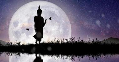 silhueta de Buda mediando com lua cheia à noite. conceito de férias budista. foto