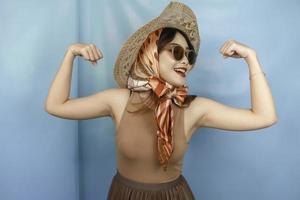 jovem mulher forte asiática mostrando seu bíceps isolado por um fundo azul foto