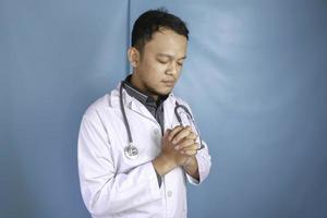 um retrato de um jovem médico asiático está orando a deus foto