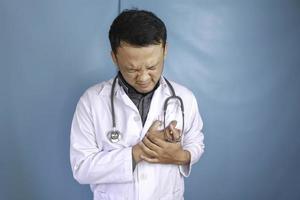 um retrato de um jovem médico asiático parece com dor no peito foto