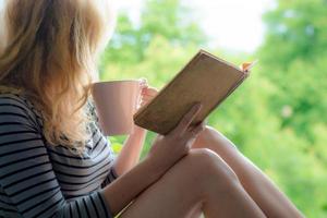 livro de leitura de mulher loira no jardim foto