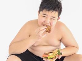 um menino gordo está comendo sanduíche feliz foto