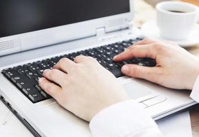 mãos digitando no teclado do computador no escritório