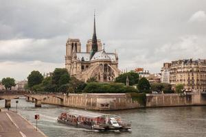Notre Dame com barco turístico no Sena em Paris