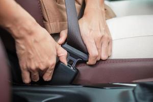 motorista de mulher apertando o cinto de segurança durante a sessão dentro de um carro e dirigindo na estrada. conceito de segurança, viagem, viagem e transporte foto