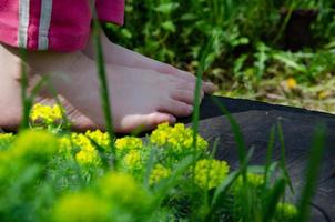 pés infantis de uma criança sem sapatos no verão na grama foto