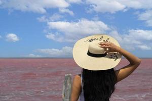 viajante de mulher de chapéu olha incrível exótico lago de sal rosa e céu azul. conceito de viagem de desejo de viajar, copie o espaço para texto foto