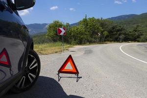 um sinal de parada de emergência de um veículo é instalado na estrada, ao lado do carro. copie o espaço. foto
