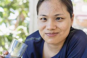 mulher jovem e atraente sentada em uma cadeira para tomar refrigerante. uma mulher gosta de beber coca no café. garota com um copo de coca-cola para relaxar nos feriados ou férias. foto