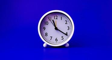 relógio branco colocado em um fundo azul o conceito de tempo e a importância do tempo foto