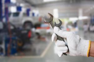 técnico segurando uma chave com fundo de centro de serviço de reparação de automóveis foto