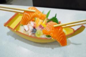 salmão em pauzinhos com sashimi japonês definido na placa do barco foto