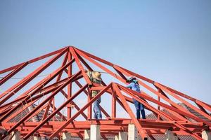 trabalhadores de solda instalando estrutura de armação de aço do telhado da casa no canteiro de obras foto