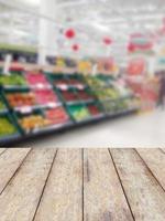 exibição de produtos de balcão de madeira com prateleiras de frutas no fundo desfocado do supermercado foto