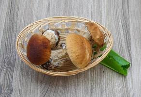 cogumelos selvagens em uma cesta em fundo de madeira foto