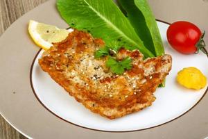 schnitzel de porco no prato e fundo de madeira foto