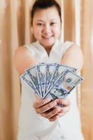 a mão direita de uma mulher branca mostrando uma maquete de nota de cem dólares para fazer compras. foco seletivo. foto