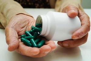 mulher idosa asiática segurando a pílula na mão, forte conceito médico saudável. foto