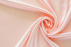 fundo de textura de pano de cetim rosa ondulado e suave elegante. foto