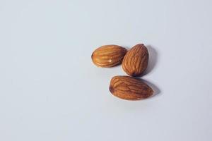 belas sementes de amêndoa colocadas em uma mesa branca. foto